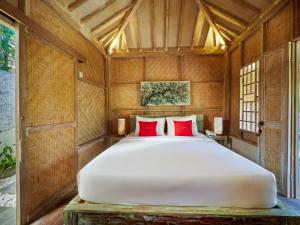 a bedroom with a large white bed with red pillows at The Tempekan Heritage in Uluwatu