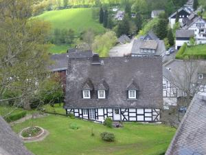 una vecchia casa bianca e nera con un cortile verde di Pension Hampel a Schmallenberg