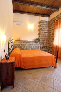 een oranje bed in een kamer met een bakstenen muur bij B&B Masseria Caporelli in San Costantino Calabro