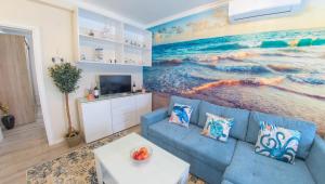 a living room with a blue couch and a painting of the ocean at Luka-Mostar Free Parking in Mostar