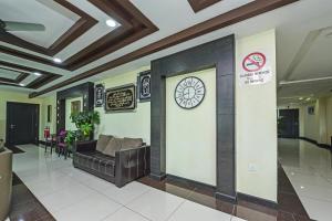 a lobby with a couch and a clock on a wall at Super OYO Capital O 90656 Sera Sentosa Inn 