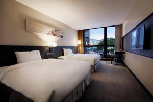 a hotel room with two beds and a flat screen tv at Platinum Hotel in Xindian