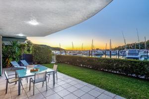eine Terrasse mit einem Tisch und Stühlen sowie einem Yachthafen in der Unterkunft Pavillions 1 - NEW Waterside Luxury with pool in Hamilton Island