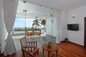 ein Wohnzimmer mit einem Tisch, Stühlen und einem TV in der Unterkunft Getaway Beach Resort Kovalam in Kovalam