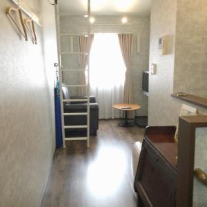 アパートメントホテル Mimoza في Sumoto: غرفة معيشة صغيرة مع نافذة وكرسي