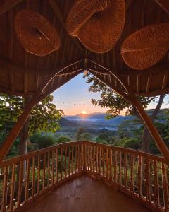 een balkon in een boomhut met uitzicht op de zonsondergang bij Bird Hills Bamboo House in Karangasem