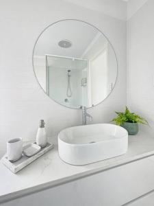 a white bathroom with a sink and a mirror at Studio Seaside Self-contained apartment in Marcoola