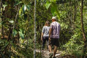 Um homem e uma mulher a caminhar por um trilho na floresta. em Ferns Hideaway Resort em Byfield