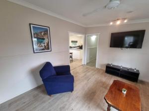 a living room with a blue chair and a tv at Glenwood Tourist Park & Motel in Grafton