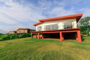 a house on top of a grassy field at StayVista's Shivom Villa 4 - A Serene Escape with Views of the Valley and Lake in Lonavala
