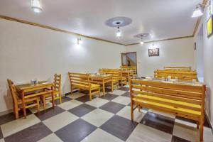 マナリにあるAyushman Hotelsのチェッカーフロアのレストラン(木製のベンチ、テーブル付)