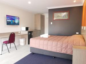 a bedroom with a bed and a desk and a chair at Homestead Motel in Dubbo