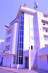 ein großes weißes Gebäude mit schwarzen Fenstern in der Unterkunft Hotel Les Orchidées in Cotonou
