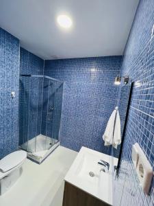 Baño de azulejos azules con aseo y lavamanos en HOSPEDAJE COLONIA VALLECAS, en Madrid
