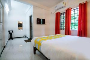 1 dormitorio con 1 cama grande y cortinas rojas en Solo Ace Hotel, en Ernakulam