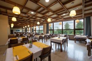 Hotel SOREA HUTNÍK I. في Vysoke Tatry - Tatranske Matliare: مطعم بطاولات وكراسي ونوافذ كبيرة