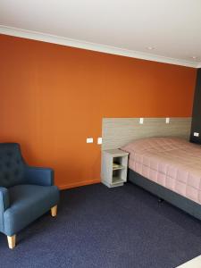 een slaapkamer met een bed en een stoel erin bij Homestead Motel in Dubbo