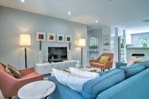 a living room with a blue couch and chairs and a tv at Modern Wilton Manors Home with Outdoor Oasis! in Fort Lauderdale