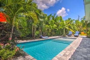 a swimming pool with two chairs and palm trees at Modern Wilton Manors Home with Outdoor Oasis! in Fort Lauderdale