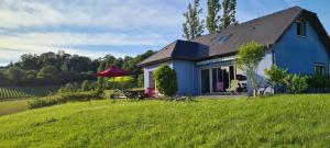 una casa azul en una colina con un campo verde en Chambres d'Hôtes Relais Milord en Estialescq