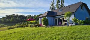 a blue house on a hill with a green field at Chambres d'Hôtes Relais Milord in Estialescq