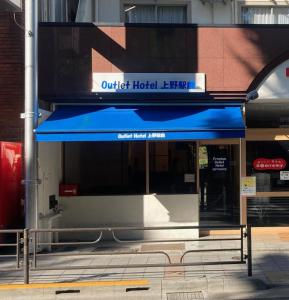 a building with a blue awning on a street at Outlet Hotel UenoEkimae in Tokyo