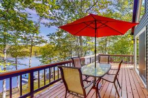 a table and chairs on a deck with a red umbrella at Marwood Lake Cottage in Wakefield