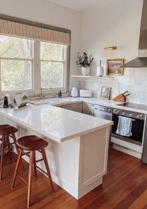 a kitchen with a large white counter and stools at Woolrich Historic Garden Accommodation in Olinda