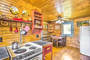 Il comprend une cuisine équipée d'une cuisinière, d'un réfrigérateur et d'une table. dans l'établissement Lovely Pet-Friendly Flat Rock Cabin from 1905, à Rising Fawn