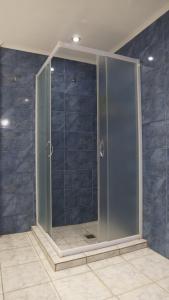 una doccia in vetro in un bagno con piastrelle blu di Romanos Patras studio a Patra Altre 31 foto