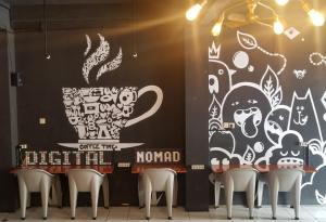 a room with chairs and a wall with a mural at CoffeeBunk Hostel in Tangerang