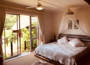 1 dormitorio con cama y ventana grande en Tropical Paradise en Southbroom