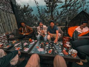 a group of men sitting around a table playing a board game at Roamate Hostel, Old Manali in Manāli