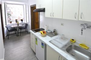 cocina con armarios blancos, fregadero y mesa en Studio In, en Dubrovnik