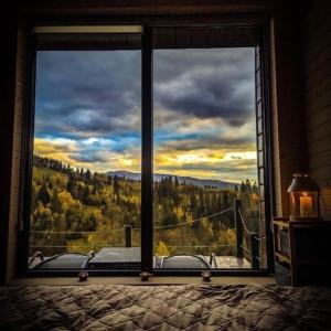 a bedroom window with a view of a forest at Ecottage котедж для двох у горах із чаном-джакузі in Slavske