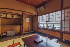 um quarto com uma mesa, cadeiras e janelas em Ryokan Motonago em Quioto