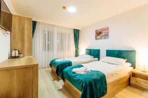 2 camas en una habitación de hotel con sábanas verdes en Vila Stadion en Câmpulung Moldovenesc