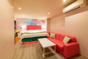 ein rotes Sofa und ein Bett in einem Zimmer in der Unterkunft Koriyama Flower Style in Tenri