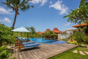 a swimming pool with a deck and an umbrella next to a house at Pondooks Joglo in Nusa Lembongan