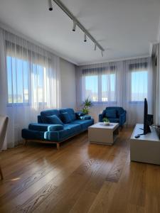 a living room with blue couches and a tv at Green Apartments Podgorica With Garage in Podgorica