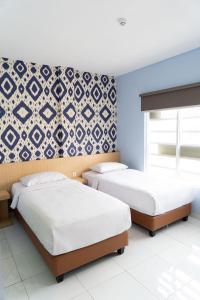 two beds in a bedroom with blue walls at Miko Rooms & Capsules hotel in Bungurasih