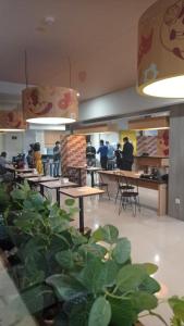 een restaurant met tafels en stoelen en mensen in de cafetaria bij Miko Rooms & Capsules hotel in Bungurasih
