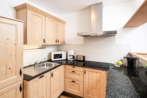 a kitchen with wooden cabinets and a sink at Fini's Apartments in Vipiteno