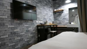 a bedroom with a tv on a brick wall at NYS Loft Hotel in Taipei