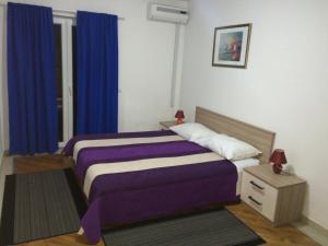 a bedroom with two beds and blue curtains at Villa Royal in Cavtat +10 photos