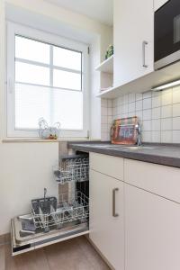 a kitchen with white cabinets and a dishwasher at Haus Strandlooper in Neuharlingersiel