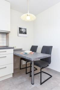 een keuken met een eettafel en 2 stoelen bij Haus Strandlooper in Neuharlingersiel
