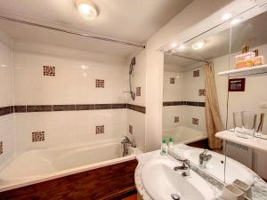 a bathroom with a sink and a tub and a mirror at Gîtes Les Villes Briend in Pluduno