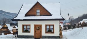 Une petite maison avec de la neige au-dessus dans l'établissement Domek u Kozika, à Krościenko nad Dunajcem
