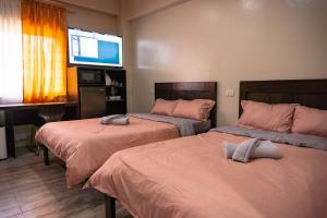 a room with two beds and a flat screen tv at Misty Hills in Baguio